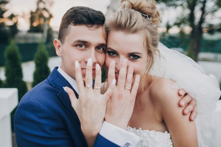 just married stylish happy bride and groom showing hands with wedding rings