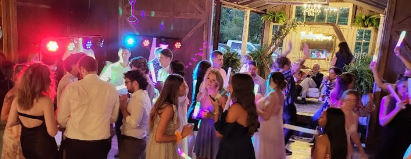 event entertainment providers. Guests dancing at an event with vibrant lighting and a DJ setup from Sandromeda Music Services.