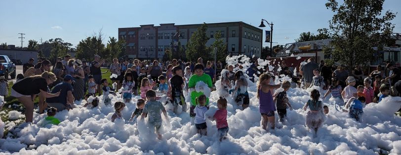 Families and children enjoying an outdoor foam party organized by Sammy's Party On Wheels.