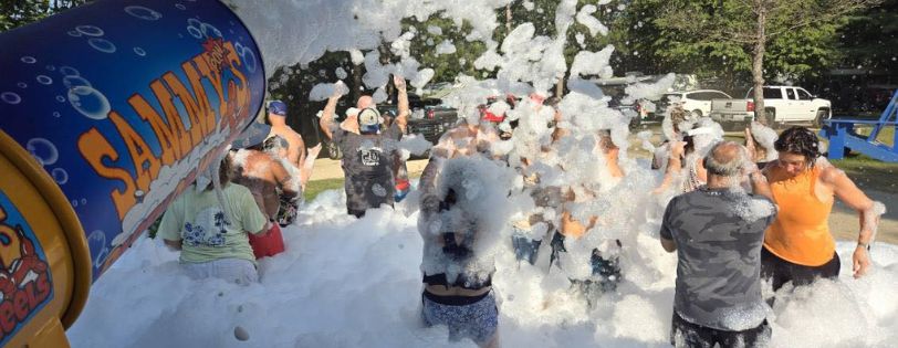 event entertainment providers . Guests having fun at an outdoor foam party with foam blasting from Sammy's Party On Wheels equipment.