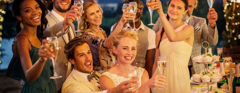 Wedding guests raising glasses in a celebratory toast.