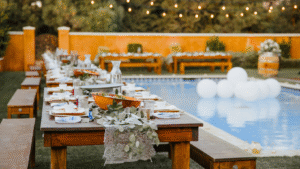 The Science of Reading the Crowd: How Our Djs Keep the Dance Floor Alive 8 backyard wedding dj. Elegant backyard wedding reception setup with wooden tables by a pool, decorated with greenery and lace runners