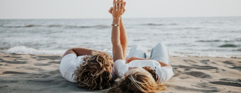 Newly engaged couple relaxing together on the beach while celebrating their engagement